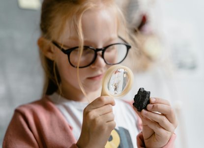 Girl with magnifying glass and rock